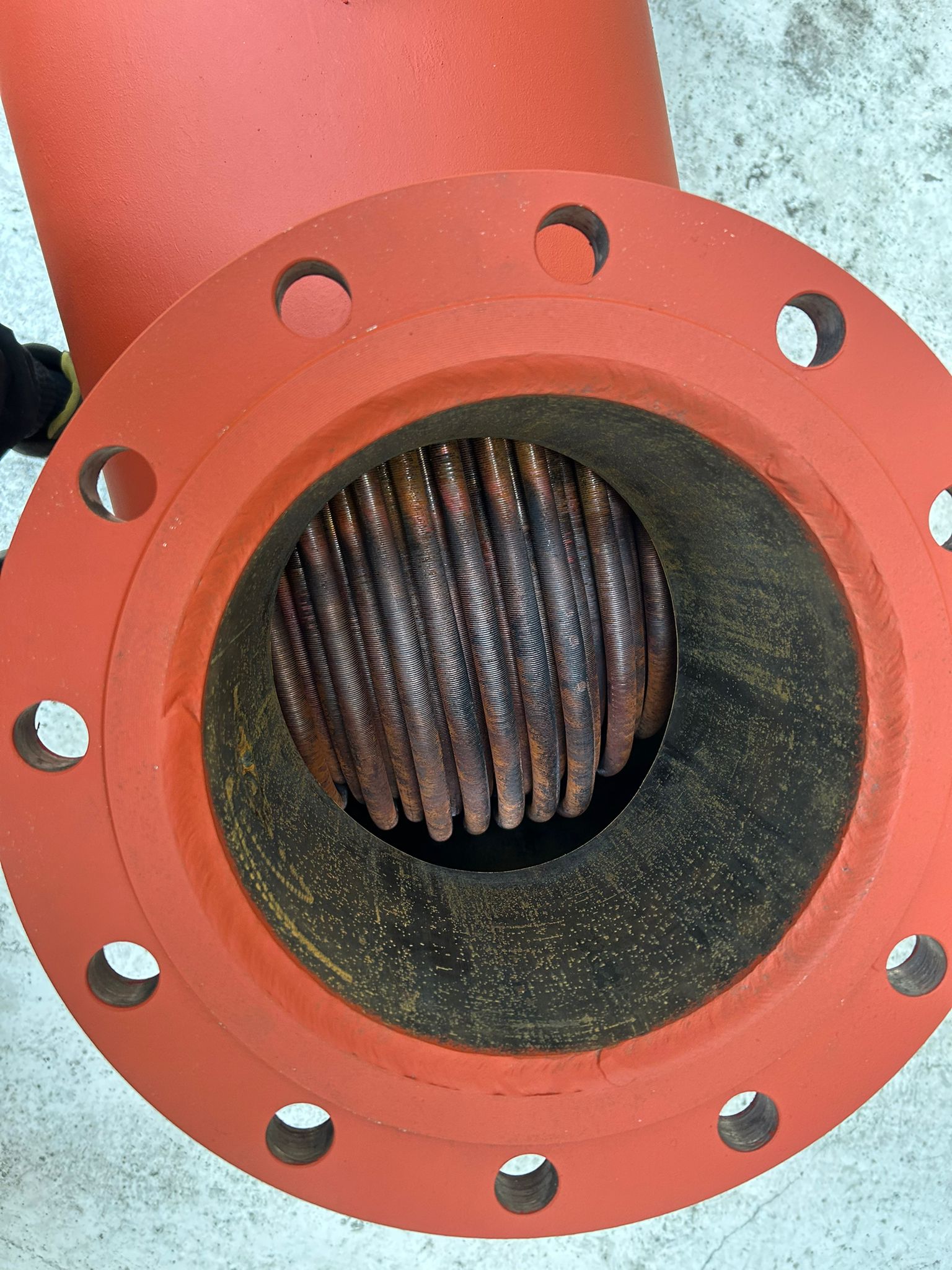 Inside a flanged nozzle of a red pressure vessel showing the internal tube coil