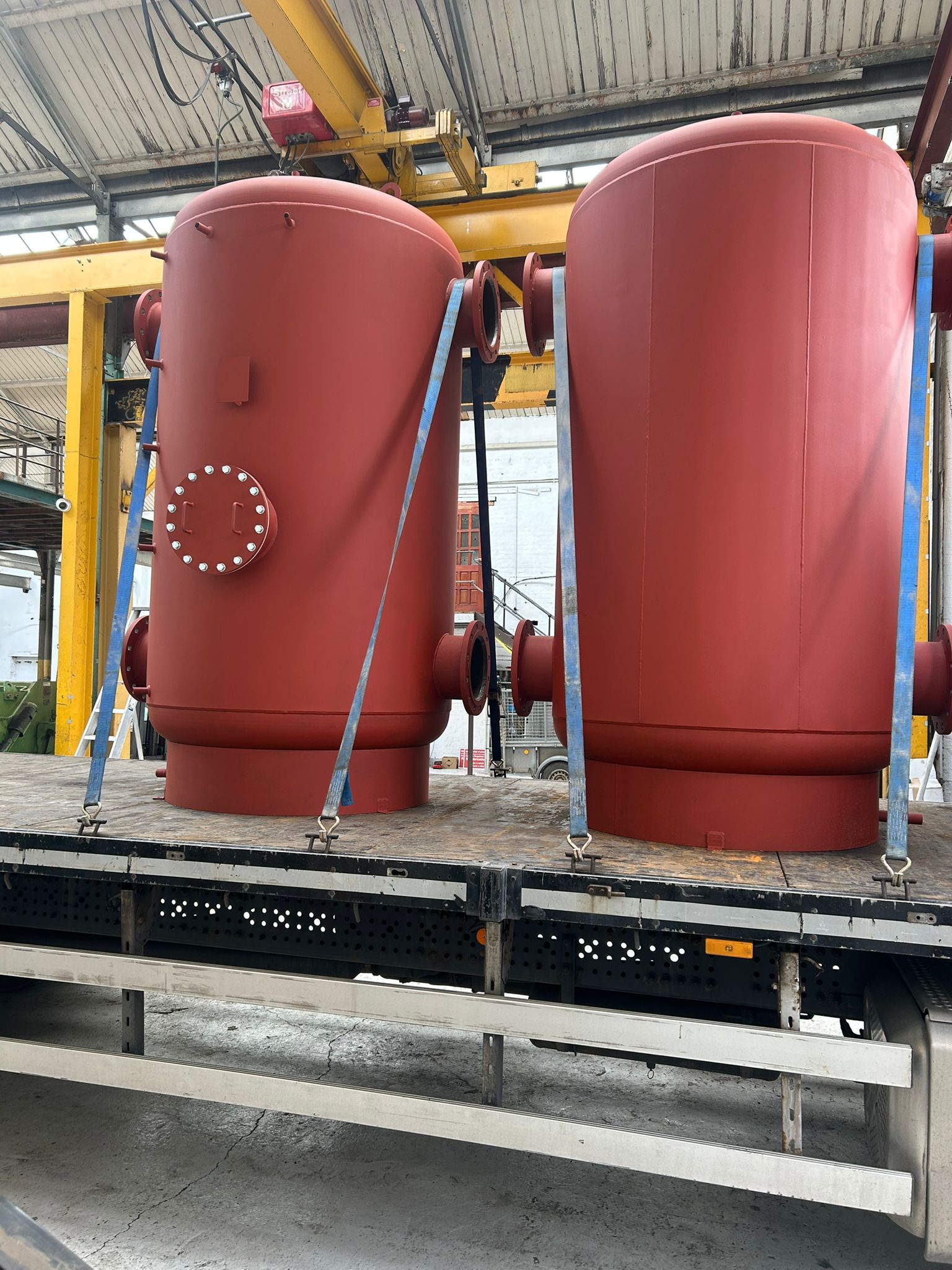 Two red fabricated pressure vessels on a lorry bed ready for delivery