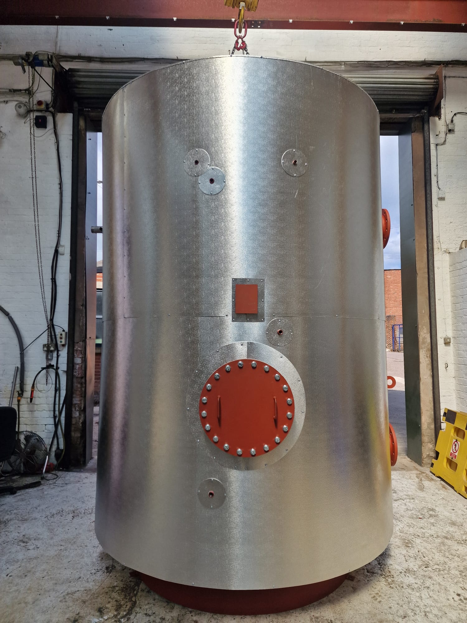 Close view of a stainless steel vessel manway and nozzle connections